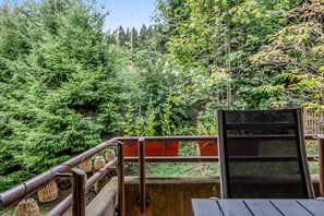 A balcony with a metal railing, a black chair, and a wooden table.