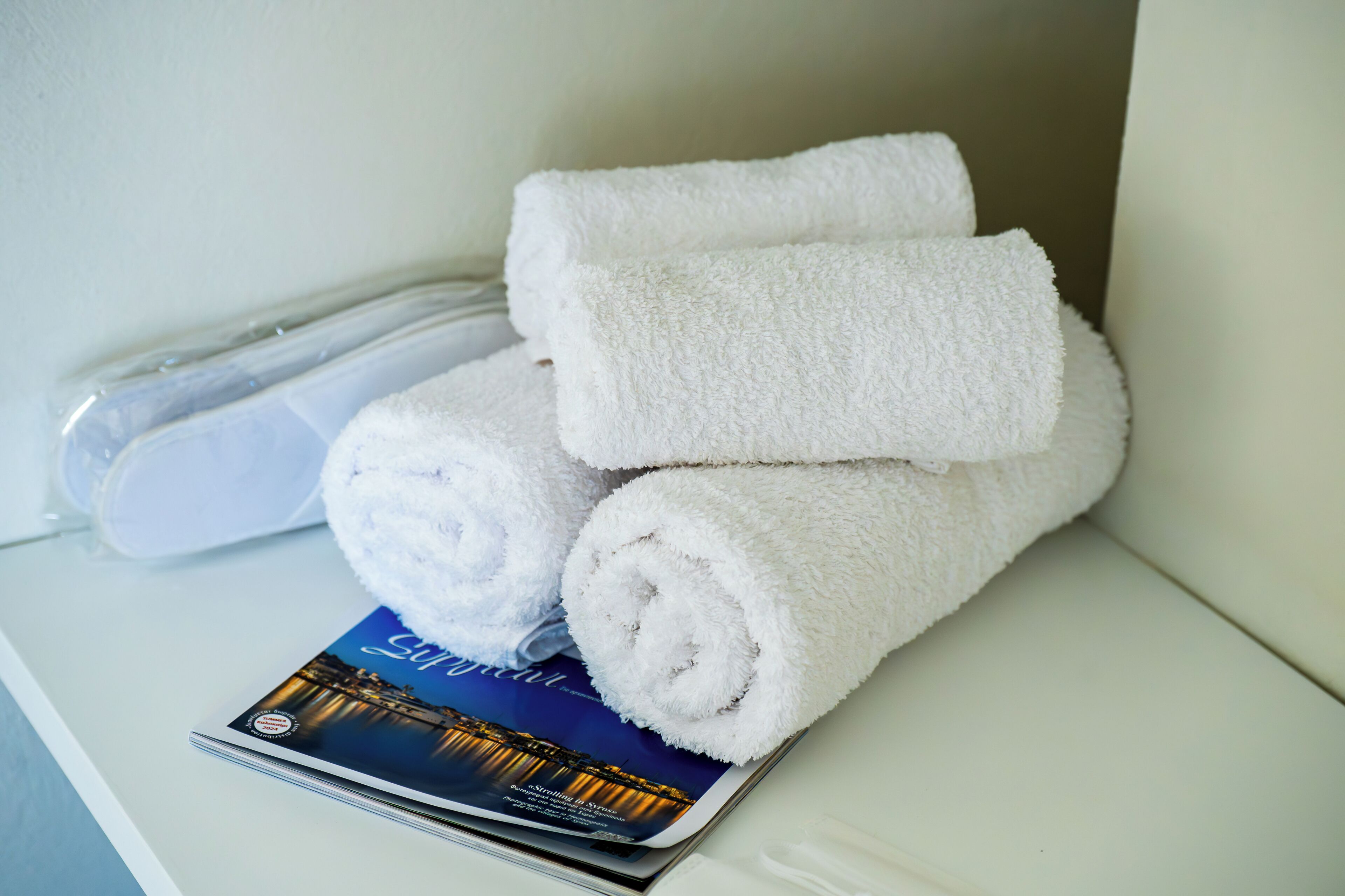 Une pile de serviettes blanches et une brochure sur une surface blanche.
