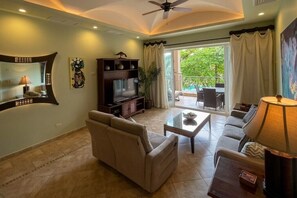 Ein Wohnzimmer mit Sofa, Couchtisch, Fernseher und Deckenventilator.