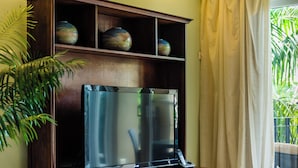 Una televisione su un supporto in legno con ripiano sovrastante contenente vasi decorativi.