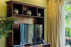 Ein Fernseher auf einem Holztisch mit einem oberhalb angebrachten Regal, auf dem dekorative Vasen stehen.