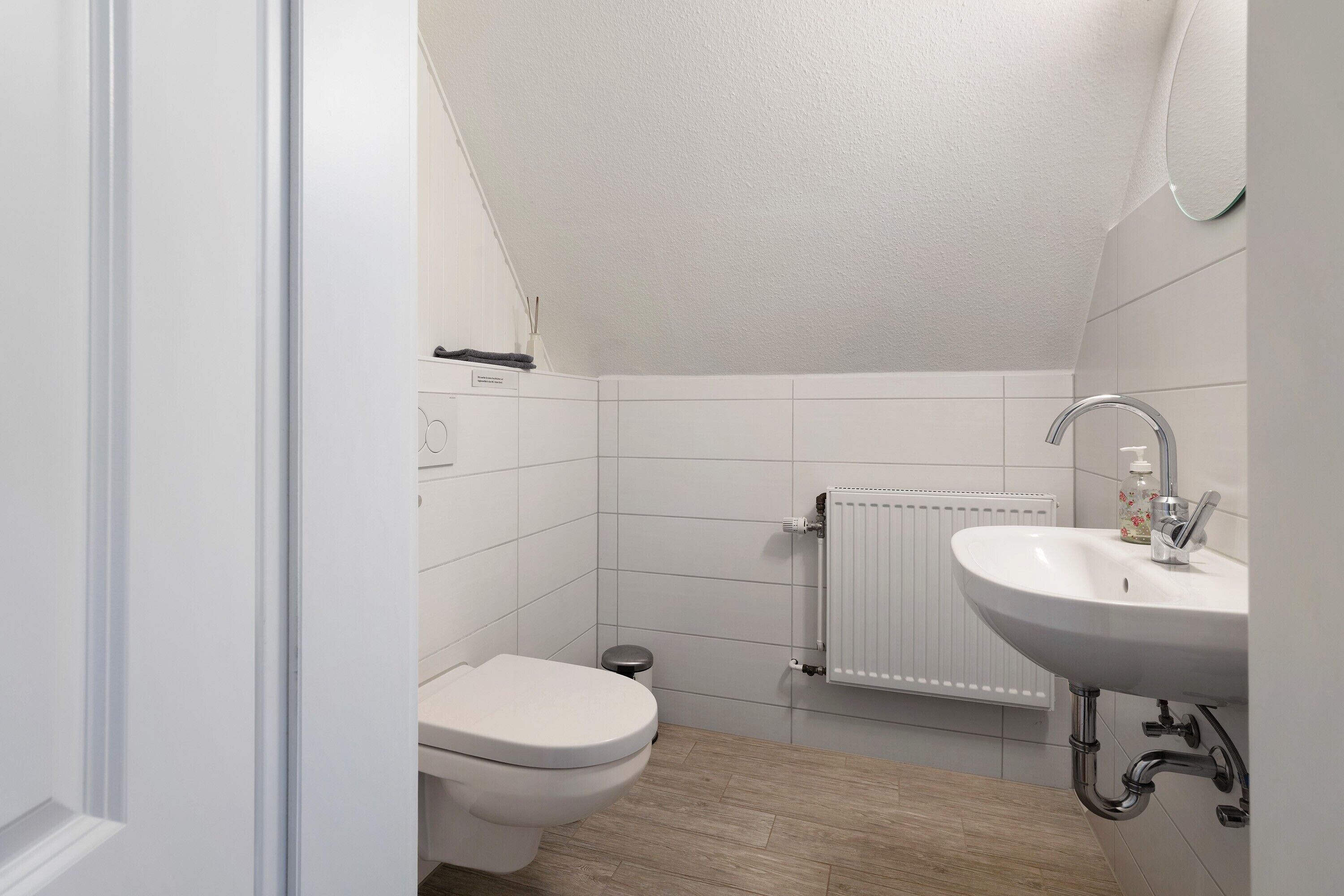 Un baño pequeño y moderno con un inodoro blanco, un lavabo y un radiador.