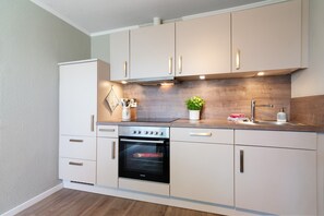 Una cocina moderna con armarios blancos, un horno de acero inoxidable y un salpicadero de madera.