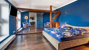Een slaapkamer met een groot bed, een bureau en een stoel.