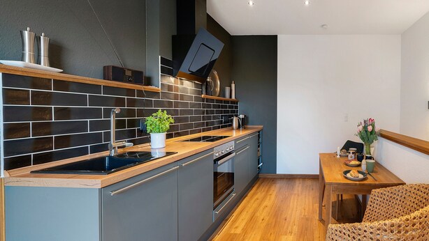 Een moderne keuken met een ingebouwde oven, een spoelbak en een eethoek met een tafel en stoelen.
