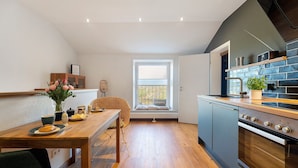 Een keuken met een houten tafel, een raam en een inbouwoven.