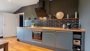 Een moderne keuken met een ingebouwde oven, een koffiezetapparaat en een waterkoker op het aanrecht.