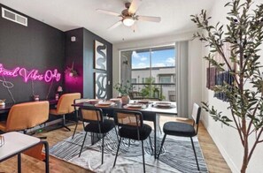A modern dining area with a black wall, neon sign, and a large window. - 2BR | Heart of DT, near Dallas Zoo & Museum (Dallas)