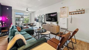 Ein modernes Wohnzimmer mit einer Couch, Sesseln, einem Couchtisch und einem Fernseher.