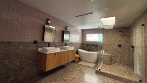 Ein modernes Badezimmer mit einem großzügigen Waschtisch, einer freistehenden Badewanne und einer begehbaren Dusche.