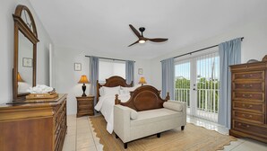 A bedroom with a bed, dresser, mirror, ceiling fan, and large windows. - Exclusive White Marlin Beach Retreat - Private Beach Access & Dock (Islamorada)