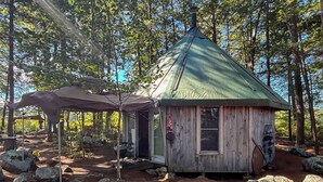 A small wooden cabin with a green roof, surrounded by rocks and trees. - 100% Private Island on Long Lake. Great for families or a group-pet friendly. (Naples)