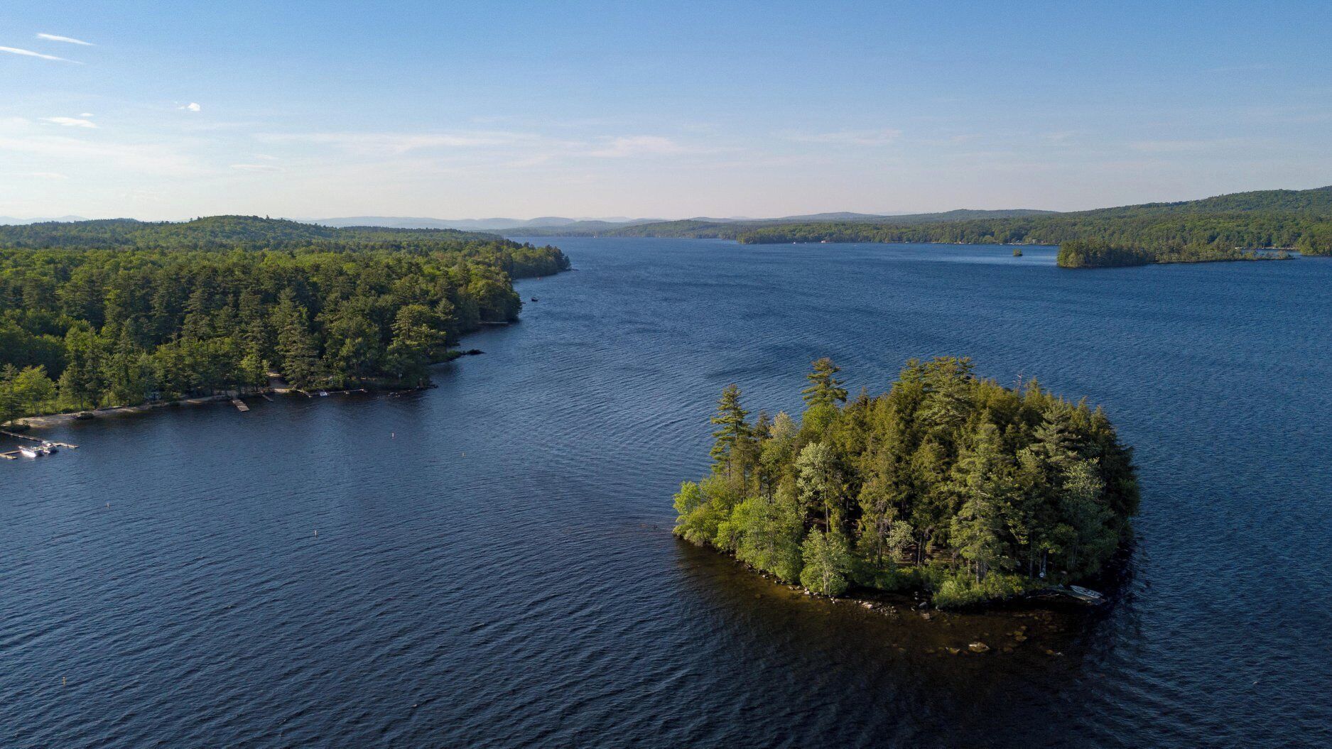 Une vaste étendue d’eau abritant une petite île recouverte d’une forêt dense.