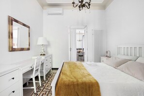 Ein Schlafzimmer mit Bett, Schreibtisch, Stuhl, Spiegel und einer Chandelier.