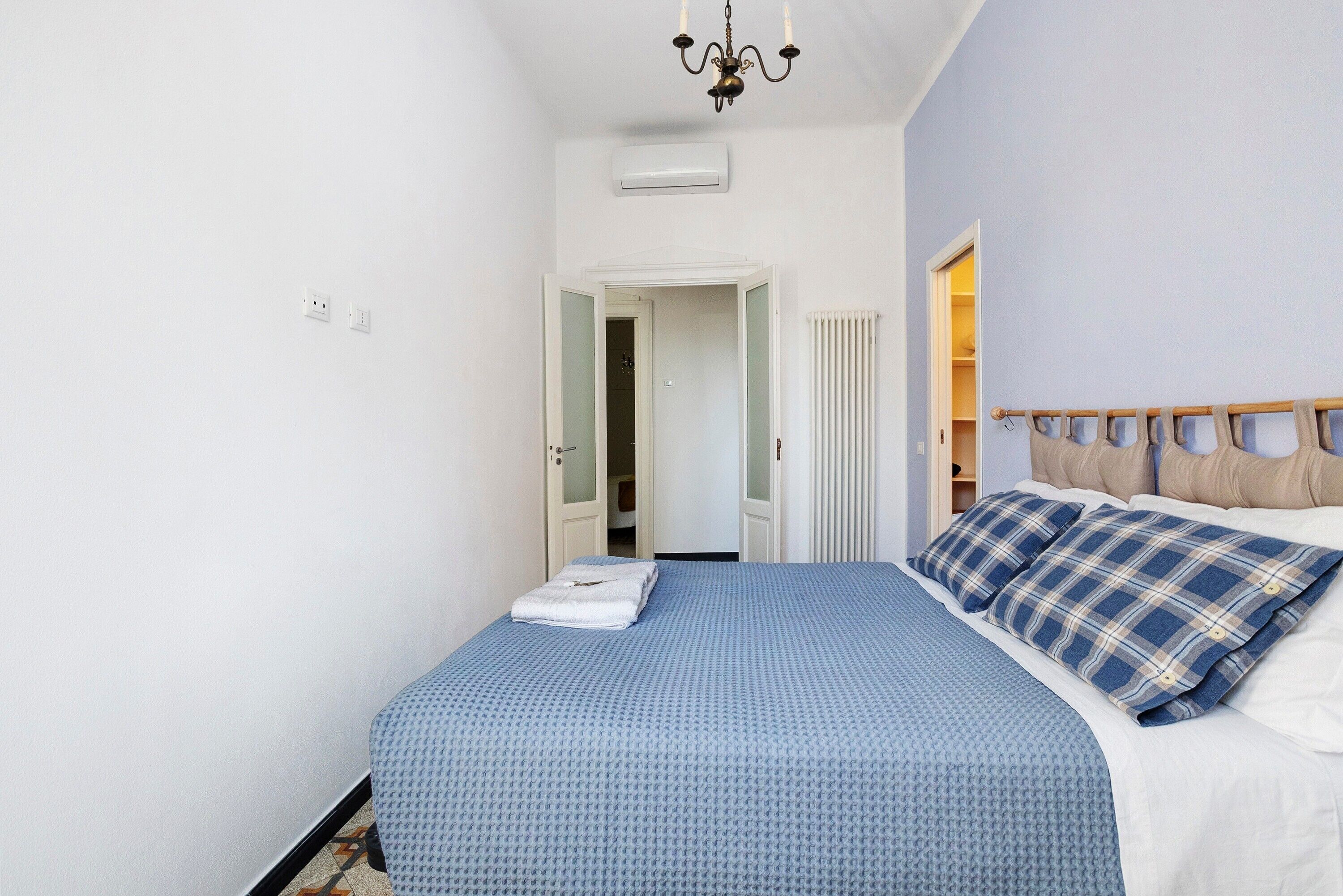 Un dormitorio con cama, candelabro, aire acondicionado, armario y una puerta que da a otra habitación.
