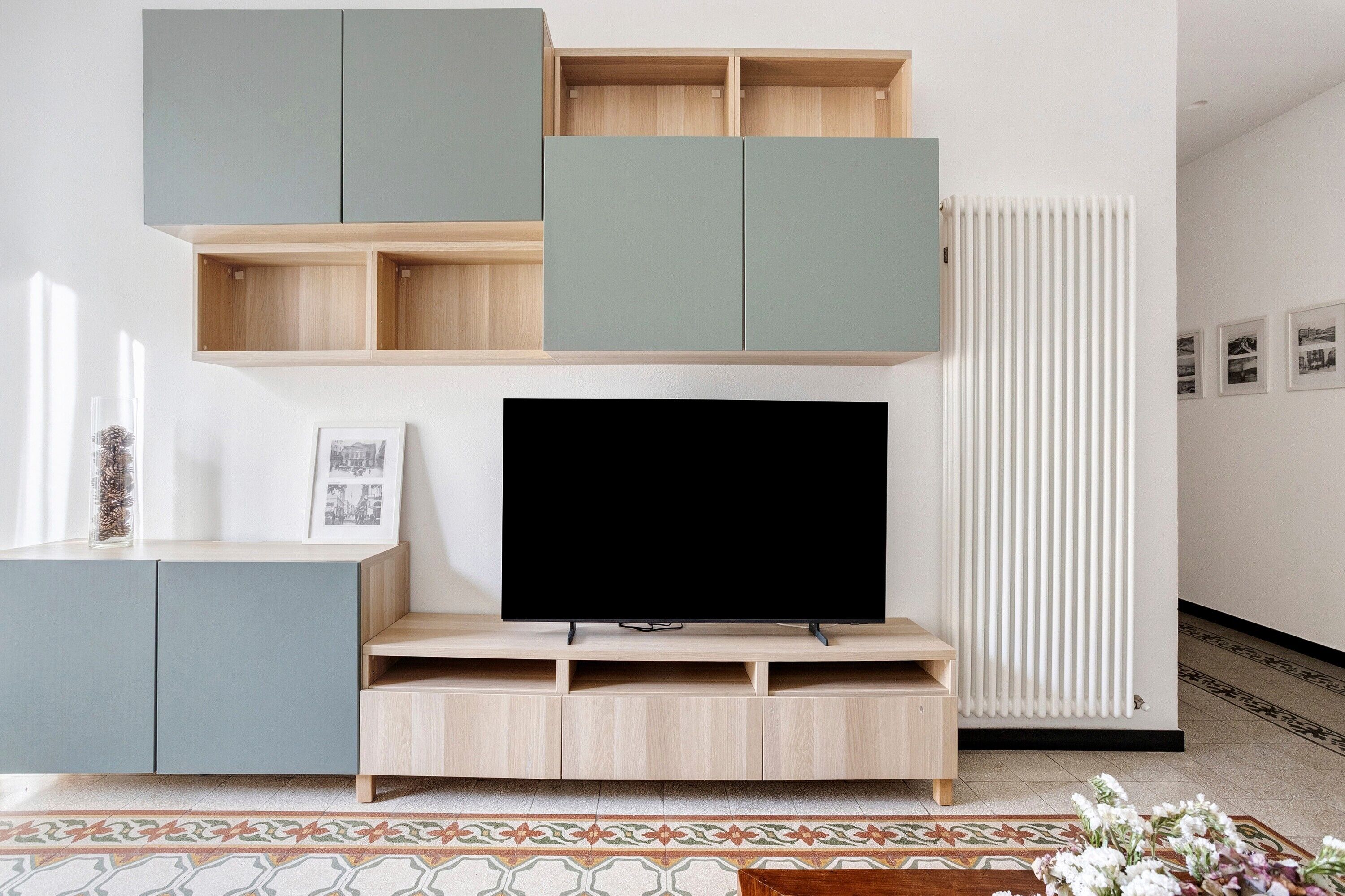 Ein modernes Wohnzimmer mit Flachbildfernseher, eingebauten Regalen und einer Heizung.