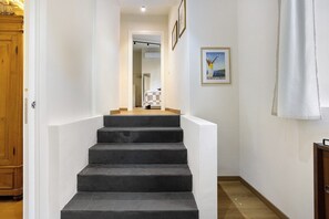 A staircase leading to a room with a checkered tablecloth, framed pictures on the wall, and a wooden cabinet. - 'Loft Fossati' Apartment with Wi-Fi and Air Conditioning (La Spezia)