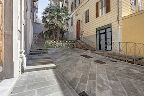 A narrow stone-paved alleyway with a staircase leading to a building entrance, surrounded by buildings with balconies and a palm tree. - 'Loft Fossati' Apartment with Wi-Fi and Air Conditioning (La Spezia)