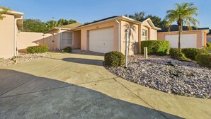 A residential area with houses, a driveway, and a palm tree. - Cozy Courtyard Villa with Pool in De La Vista (The Villages)