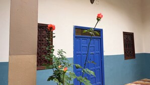 A blue door with a decorative metal grille, a wall-mounted light fixture, and a tiled floor with a geometric pattern. - An entire private Riad, just for you, for an unforgettable stay! (Tiznit)