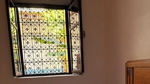 A bed with striped bedding and patterned pillows, a wooden headboard, and a window with decorative iron bars. - An entire private Riad, just for you, for an unforgettable stay! (Tiznit)