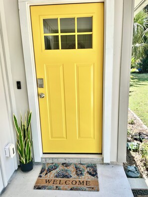A yellow door with a window, a welcome mat, and a potted plant. - Snowbird Specials ! Charming 3-bedroom 2 bath home in St Augustine FL 🏖️  (St. Augustine)