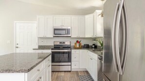 Una cocina moderna con armarios blancos, electrodomésticos de acero inoxidable y encimeras de granito.