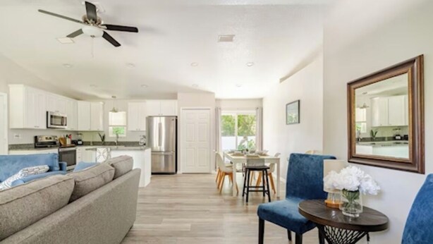 Un salón amplio con un sofá gris, un sillón azul y una zona de comedor con mesa y sillas.