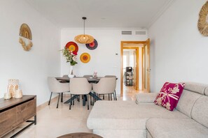 Ein modernes Wohnzimmer mit einer Couch, einem Esstisch, Stühlen und Wanddekoration.