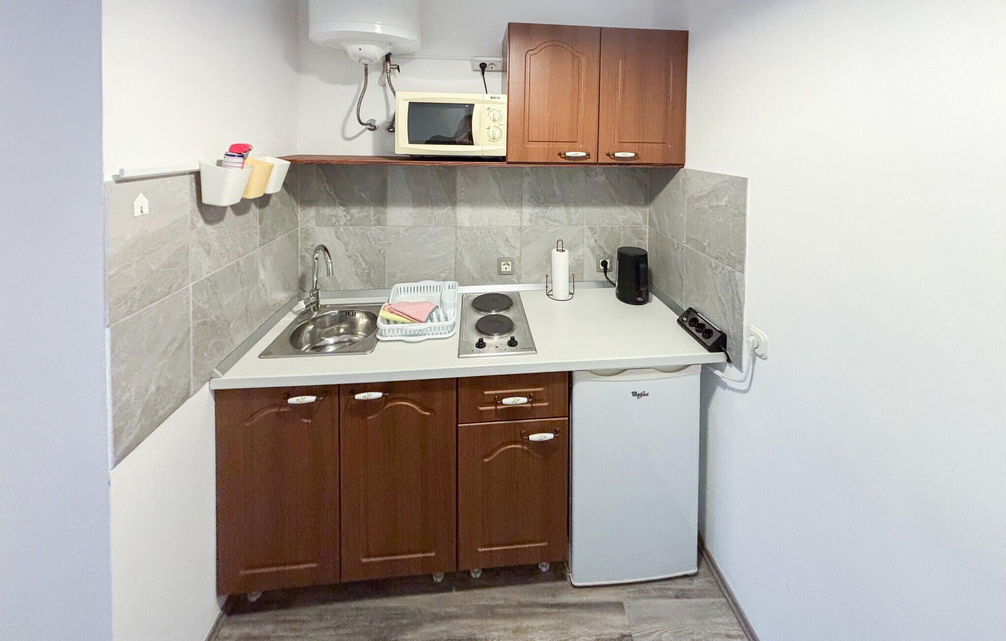 A compact kitchen with a sink, stove, microwave, and a small refrigerator.