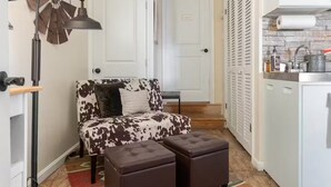 Un espacio de sala acogedor con un sofá estampado de cuero de vaca, una mesita auxiliar y un adorno de pared.