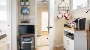 Una cocina compacta con televisor, máquina de café y microondas.