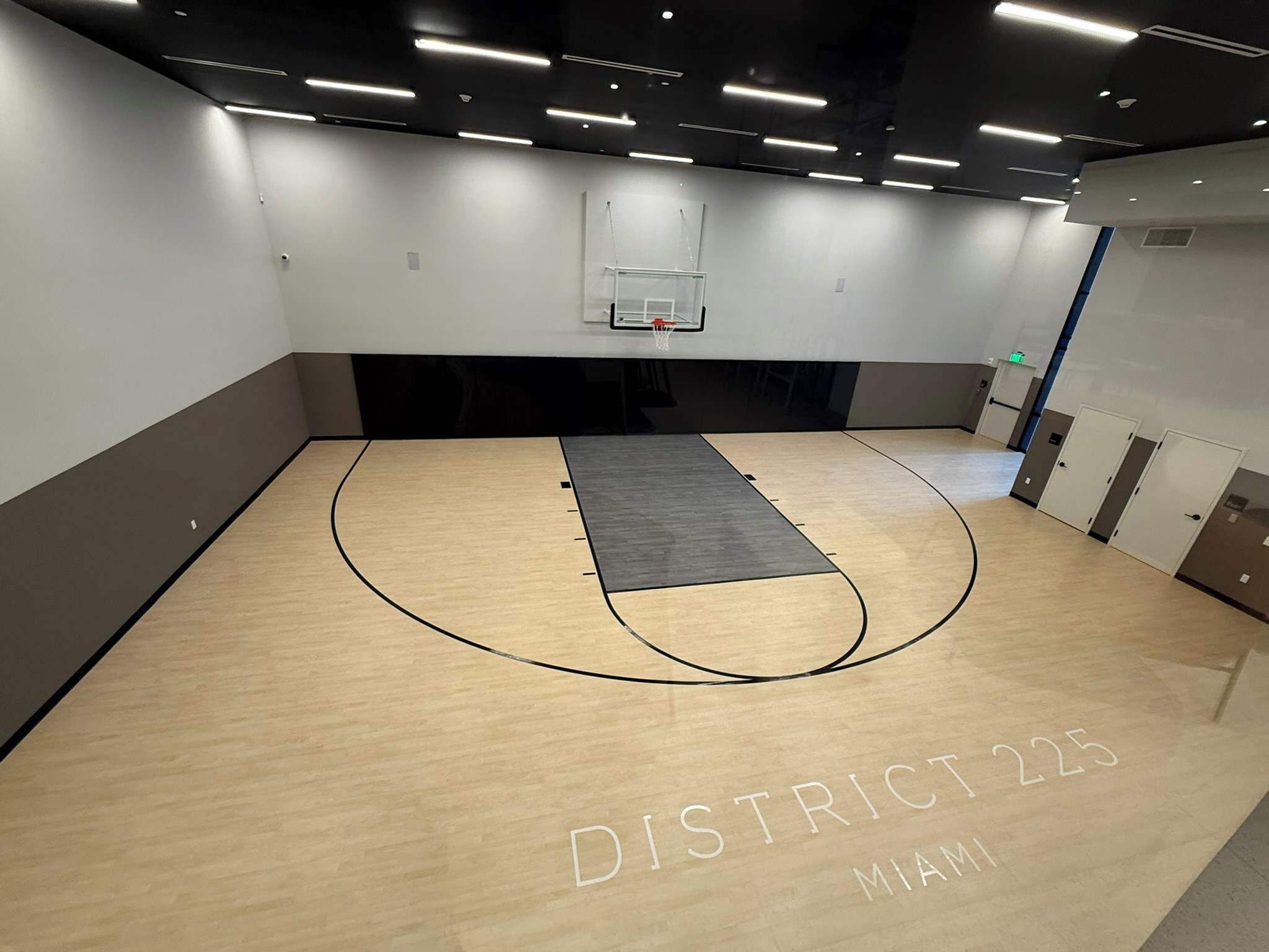 A basketball court with a net, labeled "DISTRICT 225 MIAMI," and a grey mat in the center.