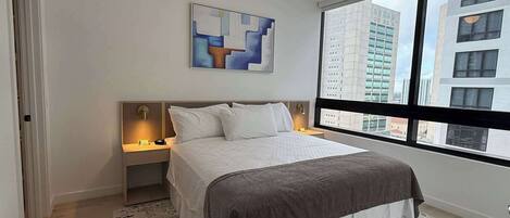 A modern bedroom with a large window, a bed, a nightstand, and a painting on the wall.