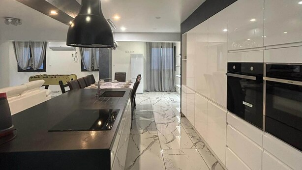 A modern kitchen with a central island, black pendant lighting, and a sleek black oven. - Beautiful house with private pool Beaujolais - 35 min from Lyon (Gleizé)