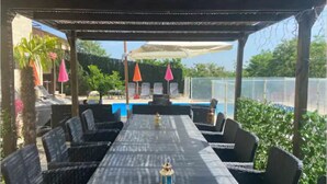 A covered outdoor seating area with a pool in the background. - Beautiful house with private pool Beaujolais - 35 min from Lyon (Gleizé)