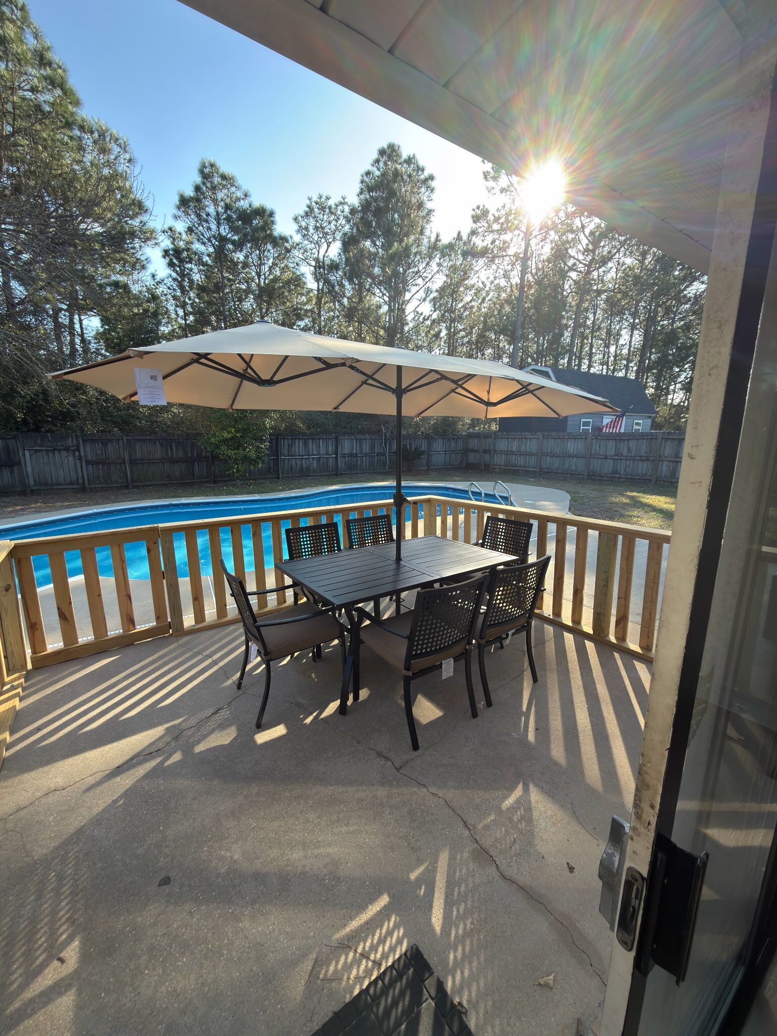 Un patio cubierto con piscina, terraza de madera y mesa con sillas.