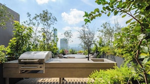 A rooftop patio with a built-in grill, seating area, and lush greenery. - Be grand del Valle by Wynwood House (Mexico City)