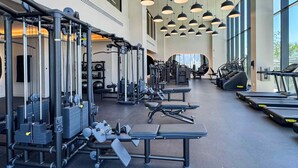 Ein Fitnessstudio mit verschiedenen Trainingsgeräten, darunter Laufbänder und Kraftmaschinen, in einem großzügigen Raum mit großen Fenstern, die viel Tageslicht hereinlassen.