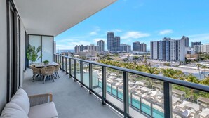 Ein Balkon mit Blick auf die Stadt, ein Pool und Sitzmöglichkeiten im Freien.