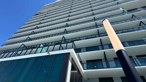 Ein modernes Hochhaus mit Glasfassade und einem markanten, senkrechten Stab im Vordergrund.