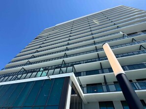 Ein modernes Hochhaus mit Glasfassade und einem markanten, senkrechten Stab im Vordergrund.