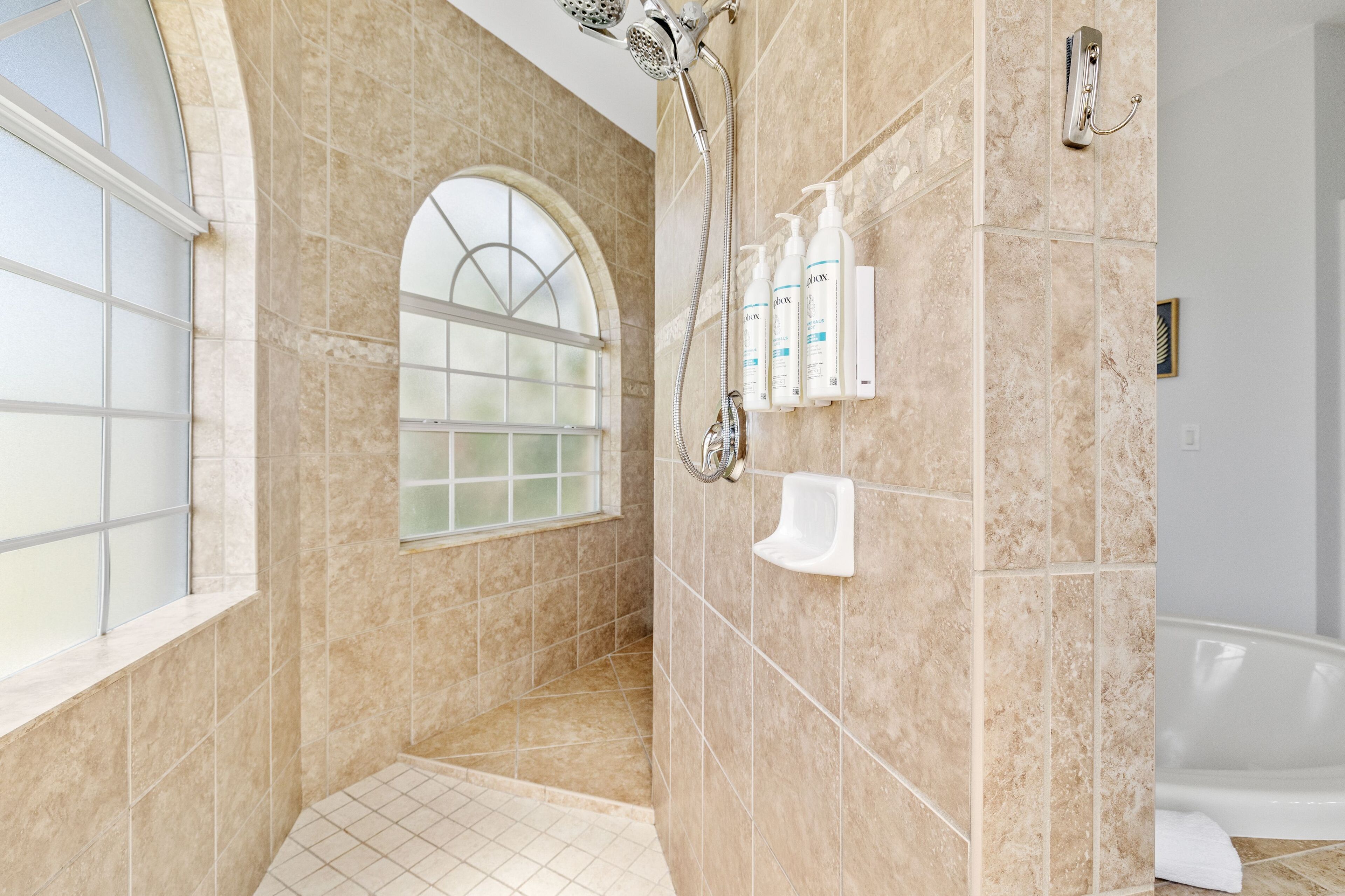 A modern bathroom with a walk-in shower, a glass-enclosed window, and a bathtub.