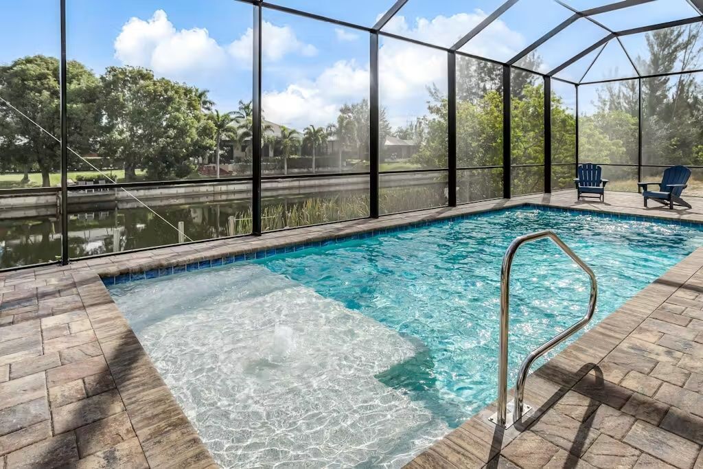 Ein Innenpool mit klarem Wasser, umgeben von einer Glaskonstruktion, und zwei Liegestühle am Pool.