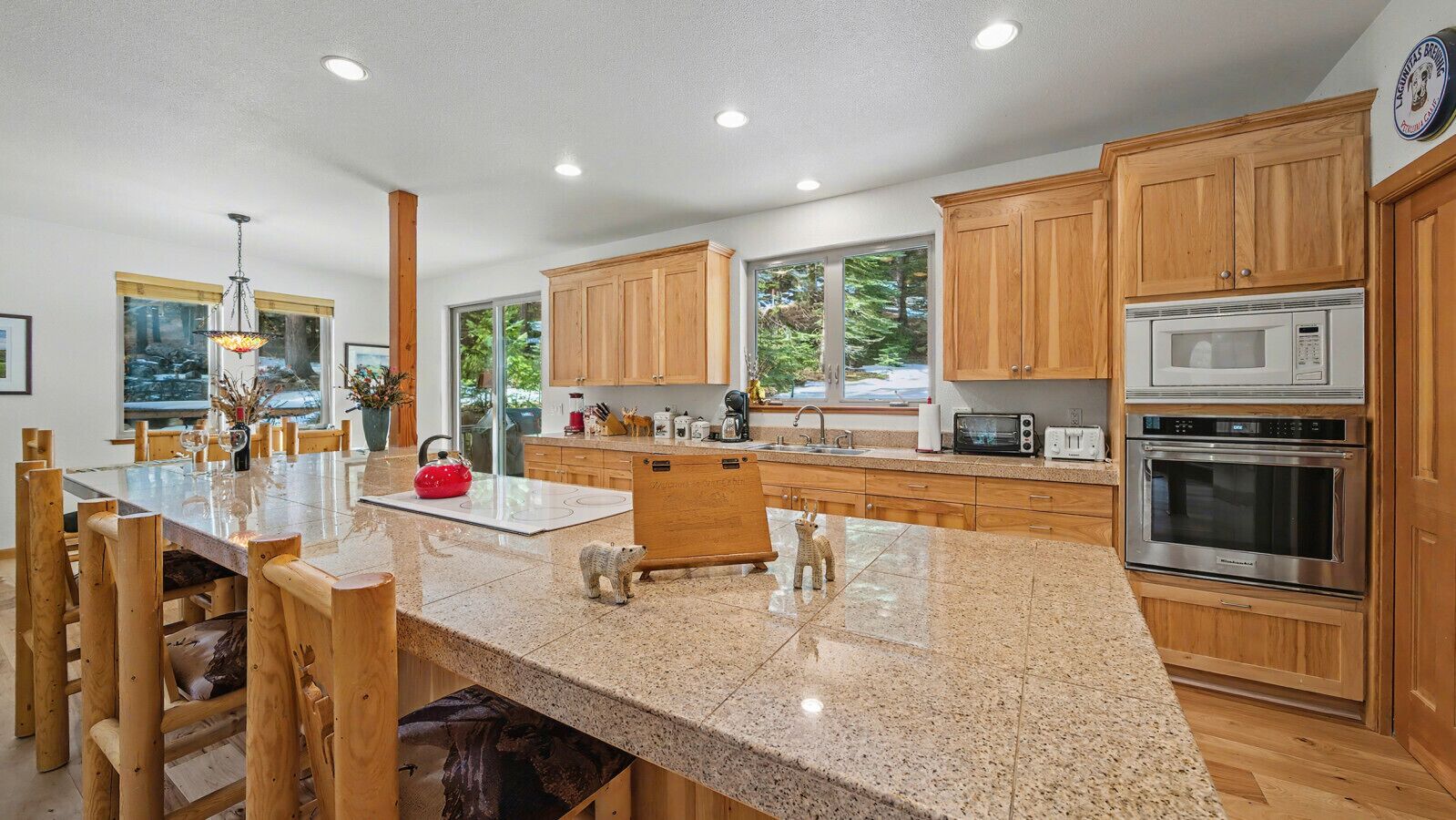 A modern kitchen with wooden cabinets, granite countertops, stainless steel appliances, and a large island with seating.