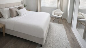 Ein Schlafzimmer mit einem großen Bett, einem Sessel und einem Fenster mit Vorhängen.