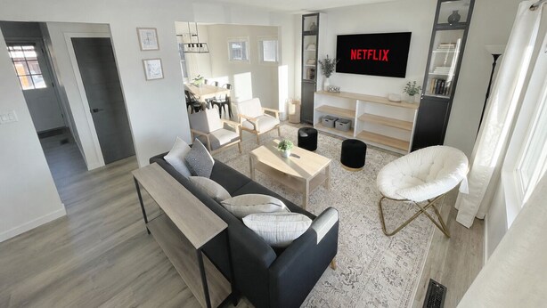 Ein modernes Wohnzimmer mit einer Couch, einem Couchtisch und einem an der Wand befestigten Fernseher.