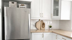 Eine moderne Küche mit weißen Schränken, einem Edelstahlkühlschrank und einer Holz Arbeitsplatte.