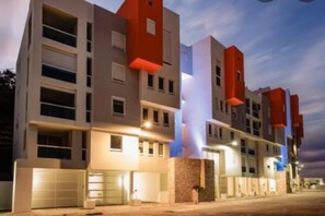 Ein mehrstöckiges Wohngebäude mit moderner Architektur, das eine Kombination aus Flachdächern und Satteldächern sowie verschiedene Fensterformen aufweist.