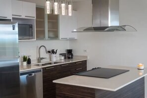 Eine moderne Küche mit einem Edelstahl-Kühlschrank, einer Mikrowelle, einer Kaffeemaschine und einem Spülbecken.